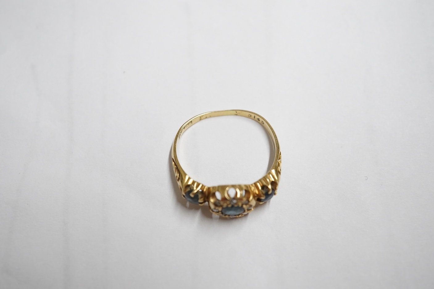 An early 20th century yellow metal and three stone sapphire set half hoop ring, the central stone bordered with rose cut diamonds, size M, gross weight 3 grams.